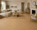 Amberwood herringbone vinyl installed in a living room with beige sectional sofa, wooden coffee table, and fireplace.