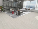 Natural Wheat waterproof luxury vinyl plank flooring installed in a modern living room with gray sofa, coffee table, and decorative items in a high-rise apartment.